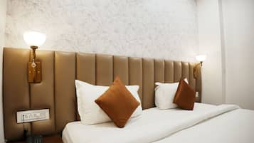 A hotel room with a large bed, two wall-mounted lamps, and a telephone on a bedside table.