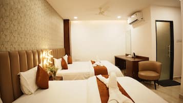 Une chambre d’hôtel avec deux lits, un bureau, une chaise, un ventilateur de plafond et un appareil de climatisation.