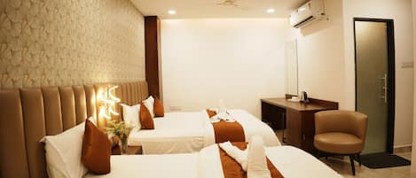 A hotel room with two beds, a desk, a chair, a ceiling fan, and an air conditioning unit.