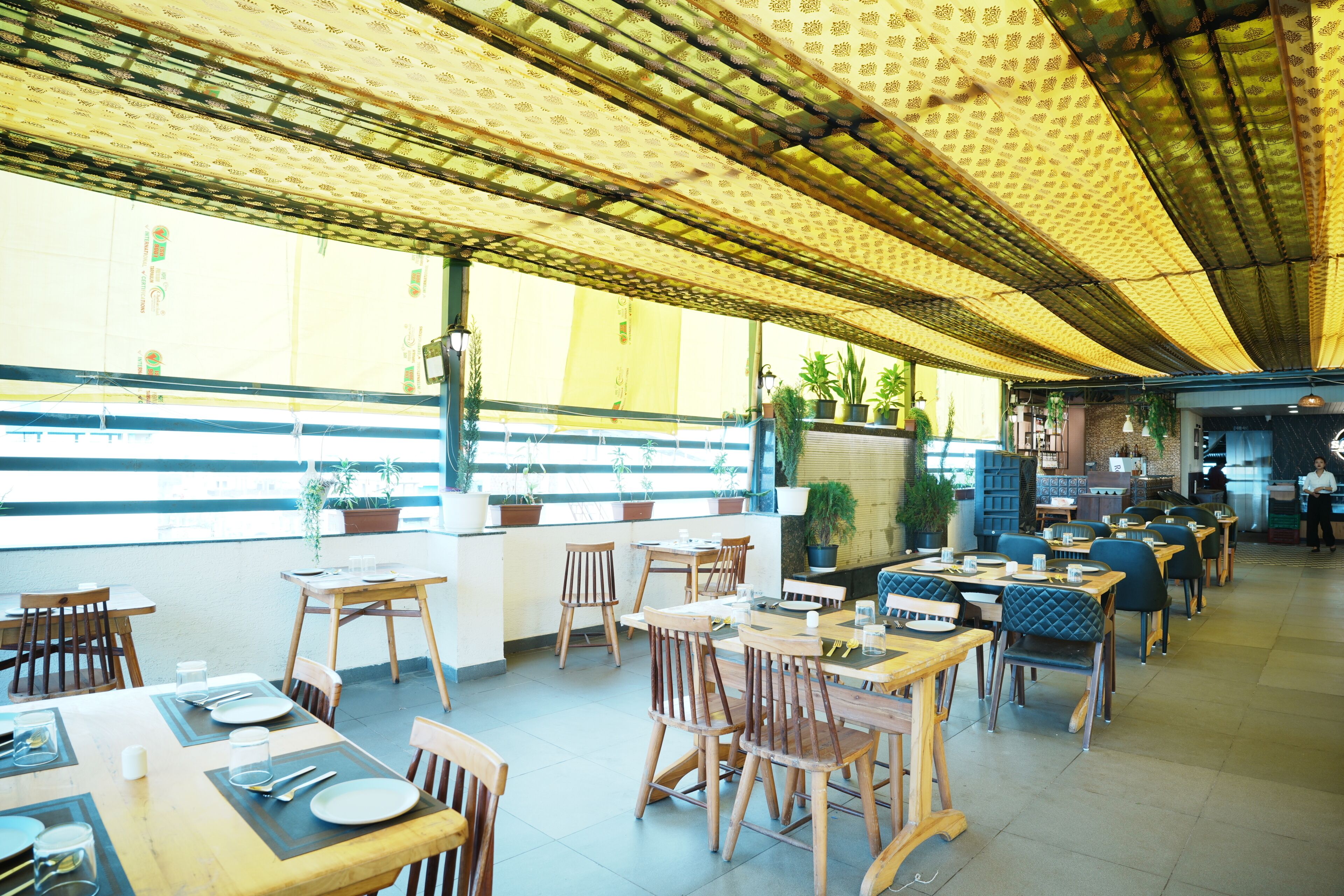 An indoor dining area with tables and chairs, a counter, and potted plants.