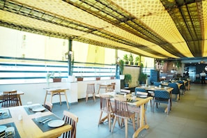 An indoor dining area with tables and chairs, a counter, and potted plants.