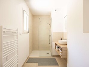 Un baño con ducha, inodoro, lavamanos y espejo.