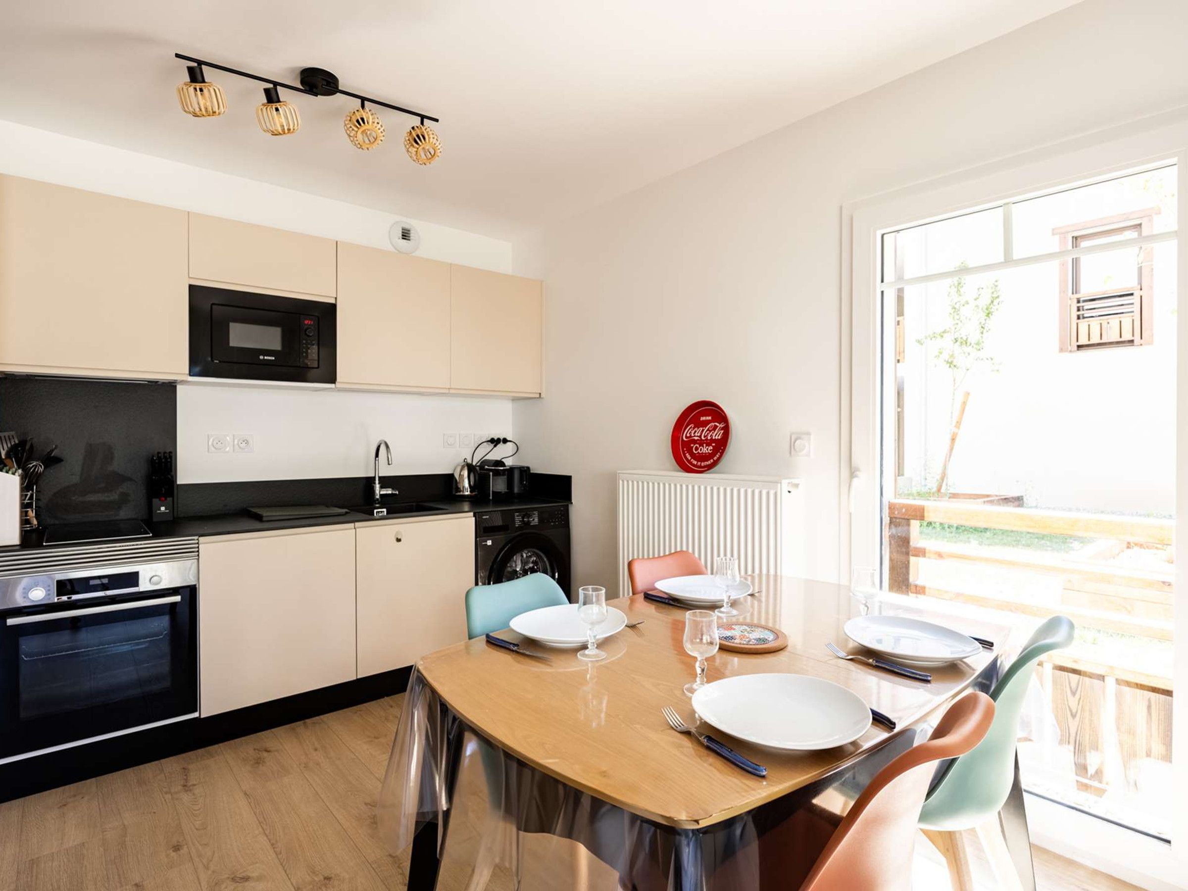 A modern kitchen with a dining area, including a table set for two with plates, glasses, and cutlery.