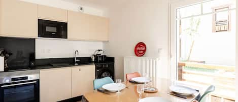 A modern kitchen with a dining area, including a table set for two with plates, glasses, and cutlery.