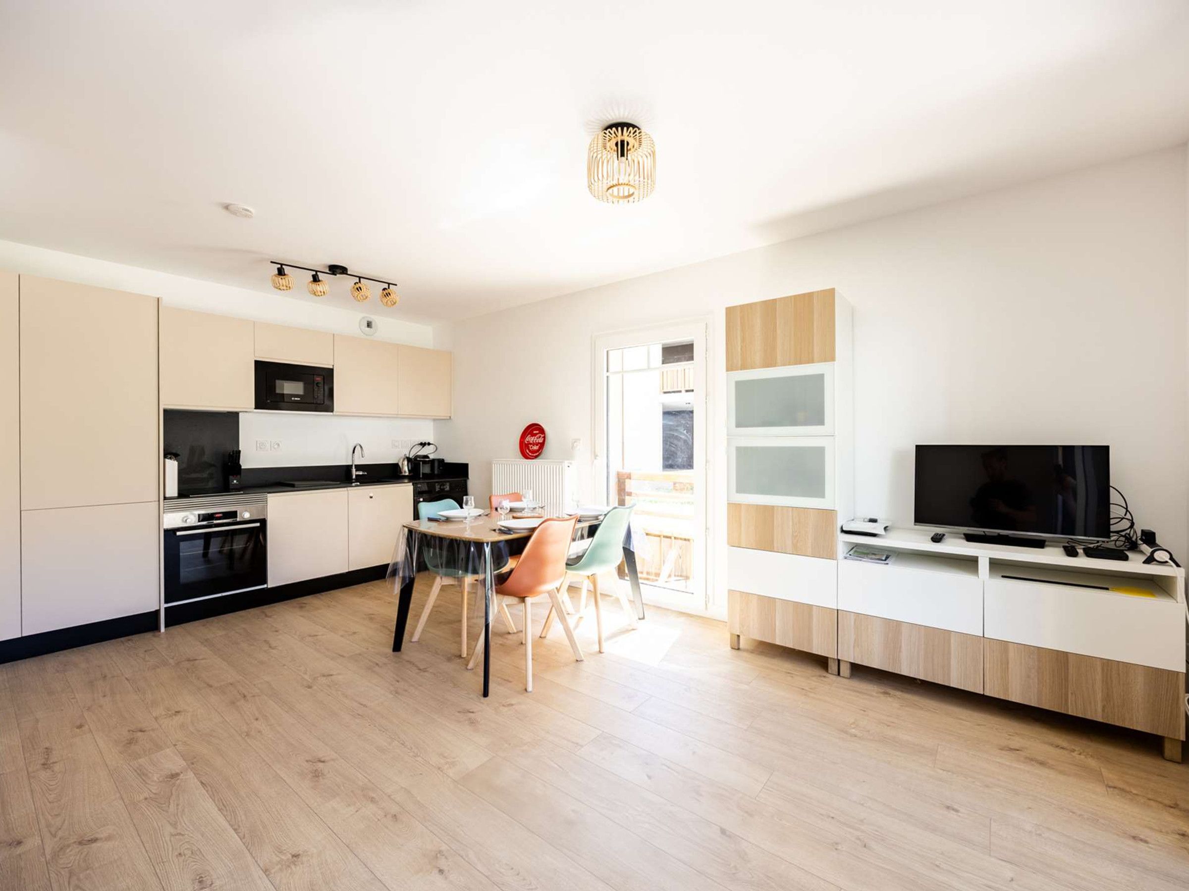 Una cocina moderna con comedor, televisor y un amplio ventanal.