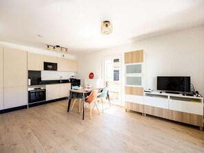 A modern kitchen with a dining area, a TV, and a large window. - Elegant studio with balcony and parking - 4 guests (Saint-Lary-Soulan)