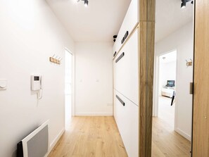 A modern, minimalist hallway with a white wall, a wooden floor, and a door leading to another room. - Elegant studio with balcony and parking - 4 guests (Saint-Lary-Soulan)