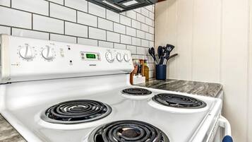 A kitchen with a white stove, four burners, and a digital clock displaying 12:49.