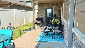 A residential backyard with a patio, outdoor seating, a stone wall, and a door.