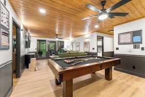 A pool table with a ceiling fan, a green sofa, and framed chessboards. - Evergreen Retreat: Fresh Remodel, Near The Island (Pigeon Forge)