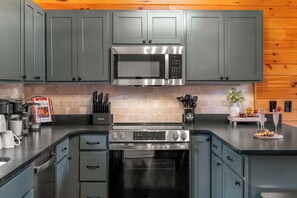 A modern kitchen with grey cabinets, a stainless steel microwave, a built-in oven, and a coffee maker. - Evergreen Retreat: Fresh Remodel, Near The Island (Pigeon Forge)
