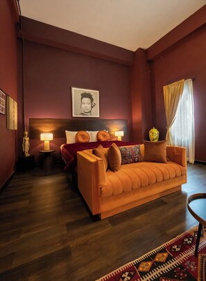 A modern hotel room with a sofa, a bed with a headboard, a bedside table with a lamp, a decorative vase, and a patterned rug. - Inpeng View Hotel (Vientiane)