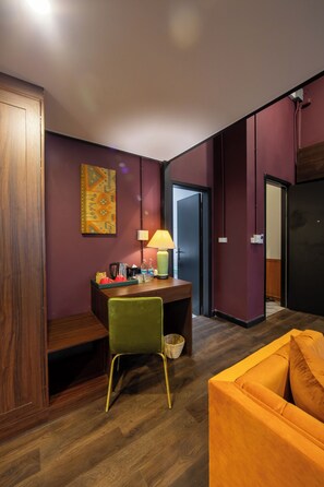 A room with a wooden desk, a green chair, a yellow sofa, and a lamp. - Inpeng View Hotel (Vientiane)