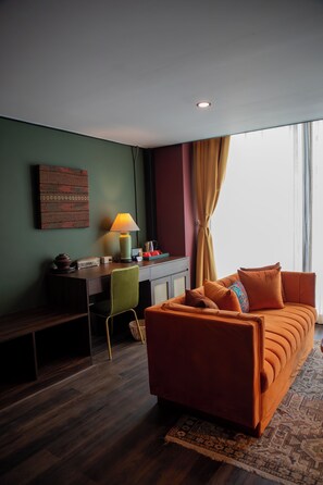 A modern hotel room with a sofa, desk, chair, and a large window with curtains. - Inpeng View Hotel (Vientiane)