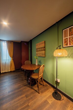 A dining area with a wooden table and chairs, a floor lamp, and a wall-mounted artwork. - Inpeng View Hotel (Vientiane)