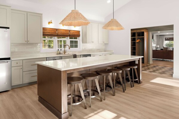 A modern kitchen with a central island, bar stools, and pendant lighting.
