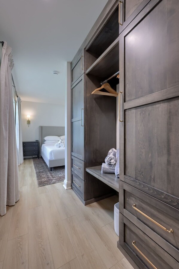 A bedroom with a bed, a wardrobe with multiple drawers, and a hanging rack.