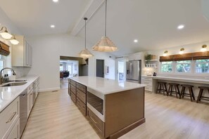 A modern kitchen with a central island, pendant lighting, and a view of the dining area.