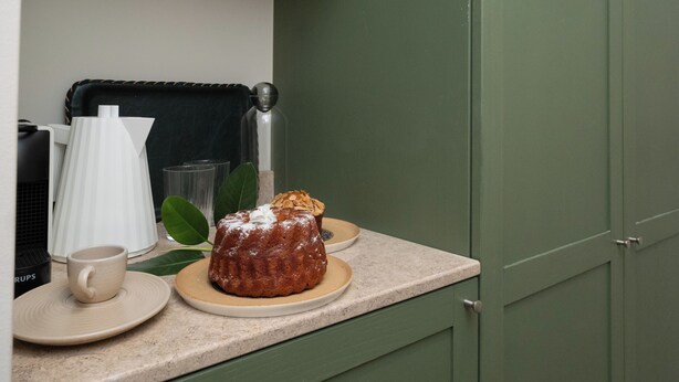 A kitchen counter with a bundt cake, a coffee cup, and a glass. - Cozy Queen, The Kodrian (Athens)