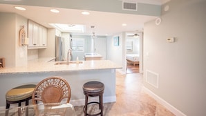 A kitchen with a central island, wooden chairs, and a dining table. - 2B/2B WATERFRONT HARBOUR POINTE VACATION CONDO! WALK TO BEACH! RESORT POOL! (Fort Myers Beach)
