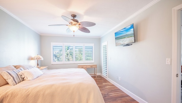 A bedroom with a bed, a ceiling fan, a window with blinds, a bedside table, and a wall-mounted TV. - 2B/2B WATERFRONT HARBOUR POINTE VACATION CONDO! WALK TO BEACH! RESORT POOL! (Fort Myers Beach)