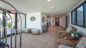 A lobby with a reception desk, seating area, and an exit sign. - 2B/2B WATERFRONT HARBOUR POINTE VACATION CONDO! WALK TO BEACH! RESORT POOL! (Fort Myers Beach)