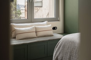 Ein Fensterplatz mit Kissen und einer Strickdecke.