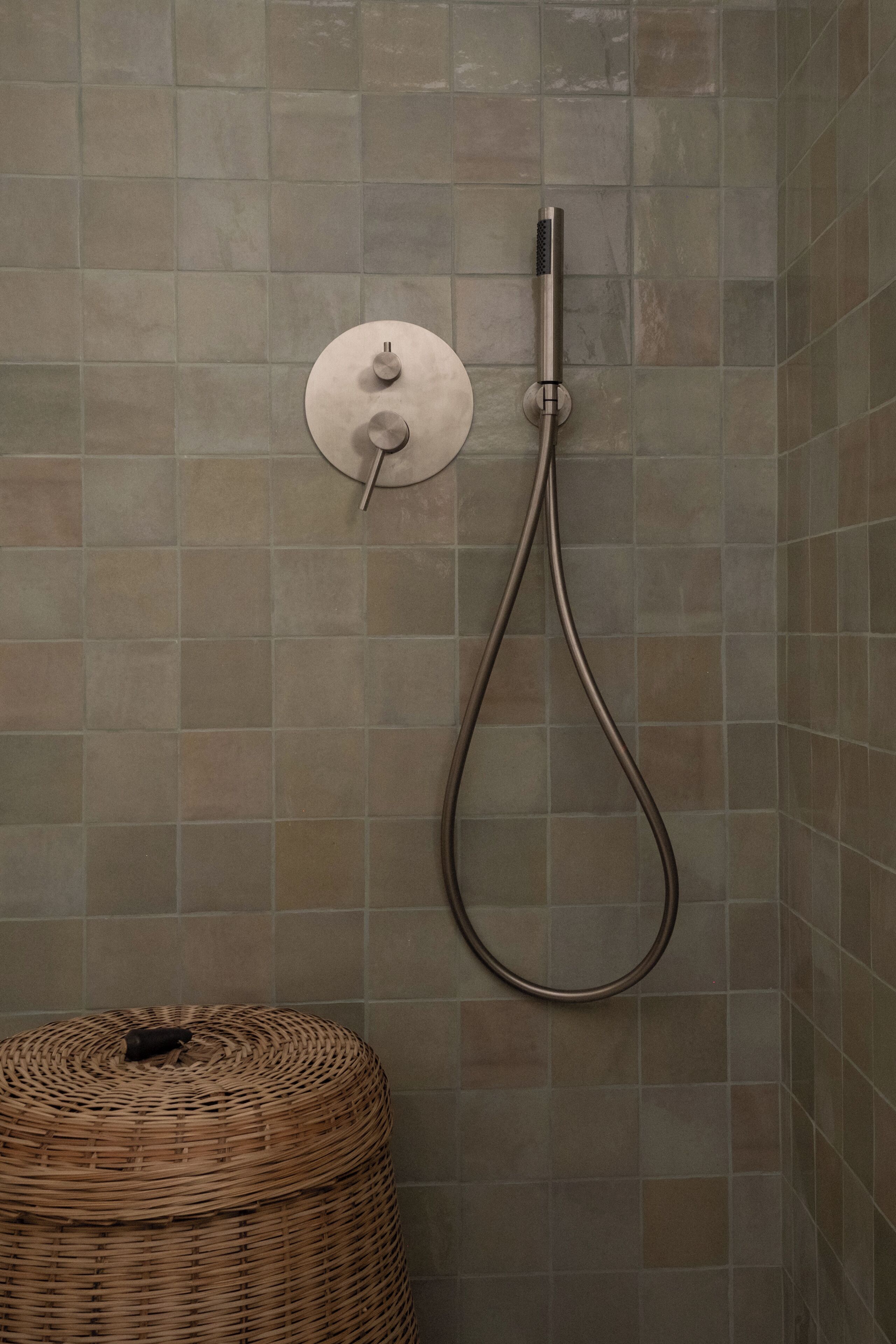 Une douche équipée d’un flexible et d’un panneau de commande fixé au mur.