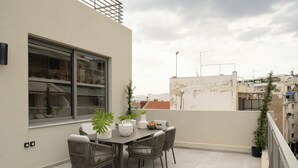 Eine Dachterrasse mit Esstisch, Stühlen und Blumentöpfen.