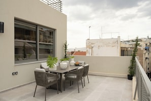 Eine Dachterrasse mit Esstisch, Stühlen und Blumentöpfen.