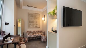 Uma sala de estar moderna com sofá, mesa de centro, televisão na parede e uma planta decorativa.
