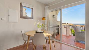 A balcony with a dining table, chairs, and a vase of flowers.