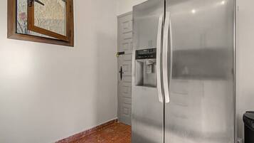 A stainless steel refrigerator with a water dispenser, a door with a lock, and a window with a wooden frame.