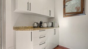 Une cuisine avec des meubles blancs, un plan de travail en granit et une fenêtre donnant sur la forêt.