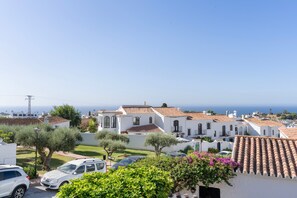 A coastal residential area with white buildings, terracotta roofs, and a clear view of the sea. - Jazmín 1A – Sea View Holiday Home in Capistrano Village (Nerja)