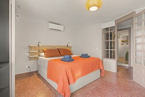 A bedroom with a bed, a wall-mounted air conditioner, a window with a view, and a door leading to another room. - Jazmín 1A – Sea View Holiday Home in Capistrano Village (Nerja)