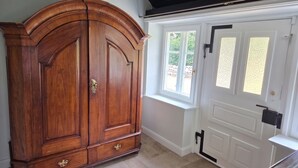 A room with a large wooden cabinet, a white door with a window, and a stone-tiled floor. - FH Luhe-Hof - Historisches Reetdachanwesen (Winsen (Luhe))