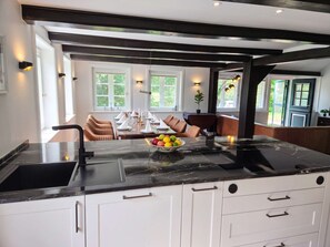 Una cocina moderna con encimera de mármol, armarios blancos y un comedor con mesa para cuatro.