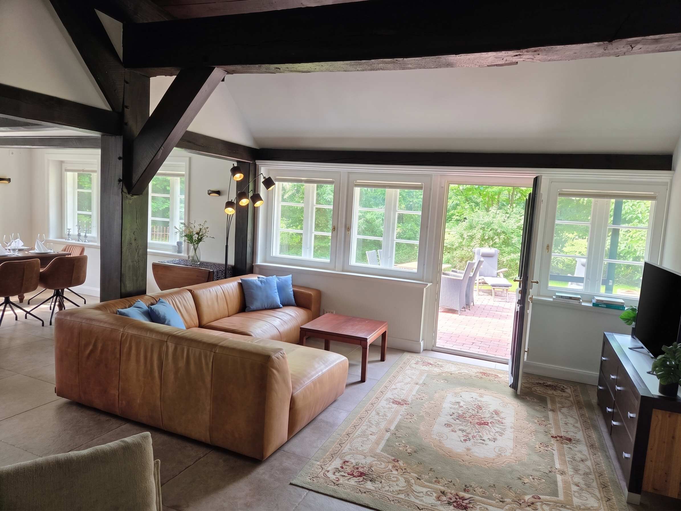 A spacious living room with a leather sofa, a coffee table, and a dining area with chairs and a table.