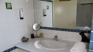 A bathroom with a white sink, a mirror, a towel, and toiletries on the counter. - La Halte Solognote (Brinon-sur-Sauldre)