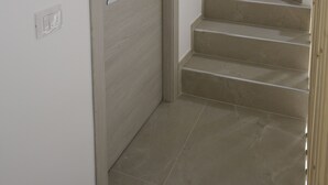 A staircase with a light-colored wooden door and a white handle. - Room with all the amenities (Termini Imerese)