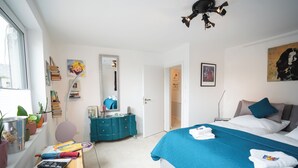Ein Schlafzimmer mit Bett, Schminktisch, Spiegel und Fenster.