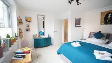 Ein Schlafzimmer mit Bett, Schminktisch, Spiegel und Fenster.