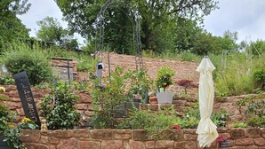 Eine Terrasse mit Steinmauer, Blumentöpfen und Gartenmöbeln.