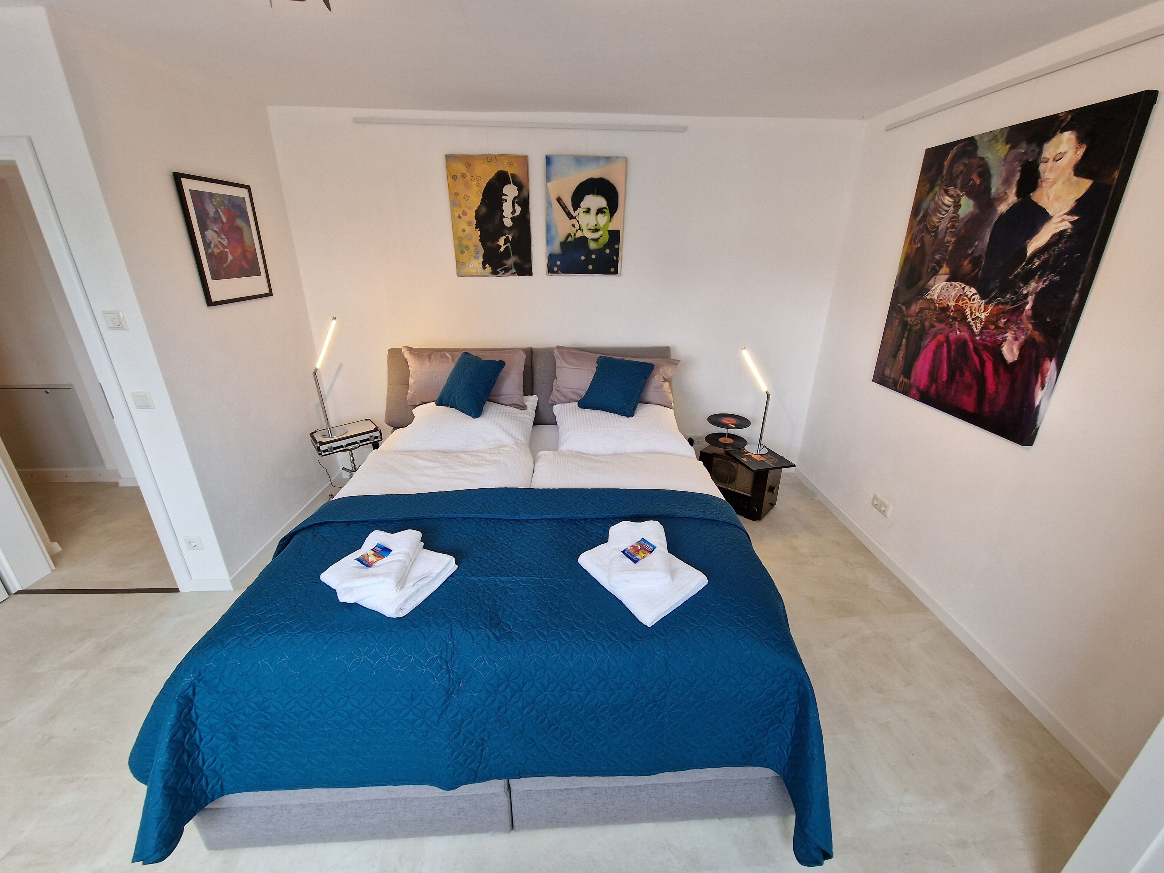Ein Schlafzimmer mit einem großen Bett, zwei Nachttischen und Bildern an den Wänden.