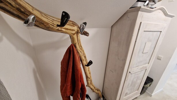 Ein Holz-Kleiderhaken mit einem Handtuch und einem Paar Schuhen daran.
