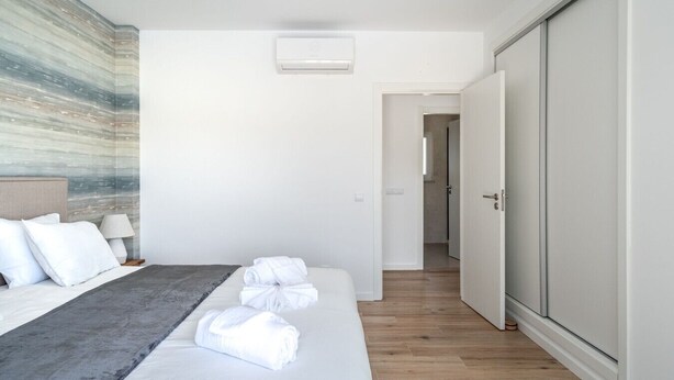 Een hotelkamer met een bed, nachtkastje met lamp, een wandairconditioner en een kledingkast.