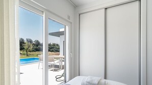 Een slaapkamer met een bed, een raam en uitzicht op een buitenzwembad.
