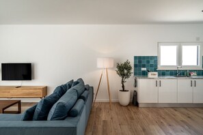 A modern living room with a sofa, a television, and a floor lamp. - Mosteiros Escape with Pool & BBQ by Lisbeyond (Mosteiros)