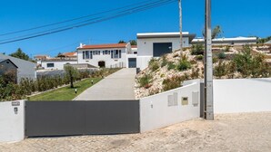 Una entrada tancada amb reixa a una propietat, amb un carrer d'accés pavimentat que condueix a un edifici modern amb garatge.
